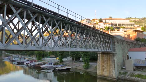 railway iron bridge in douro valley with boats in the marina in pinhao, portugal