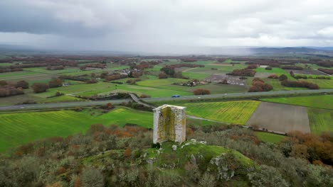 Hochwinkel-Luftumlaufbahn-Des-Sandiás-Turms,-Ourense,-Spanien,-über-Ackerland-An-Einem-Stürmischen-Tag