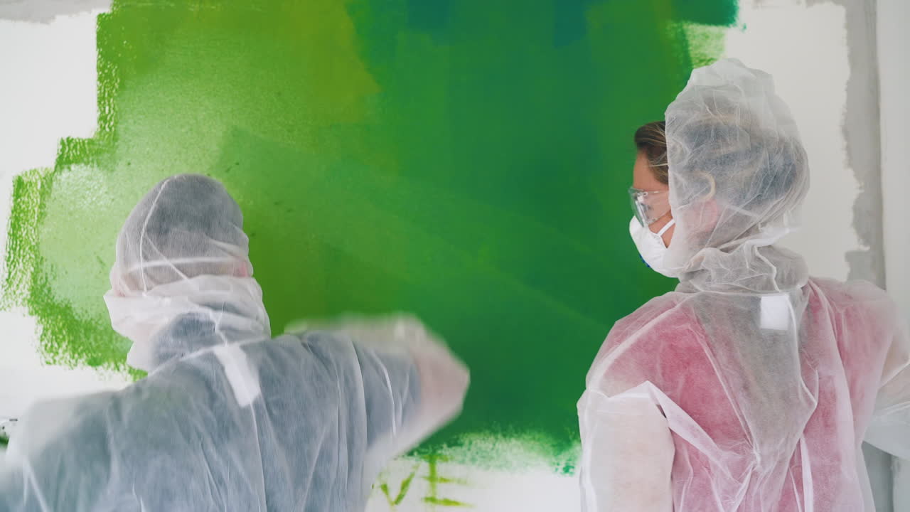 여자 는 집 에서 옷 을 입고 춤 을 추는 남자 근처 의 방 벽 을 칠 한다