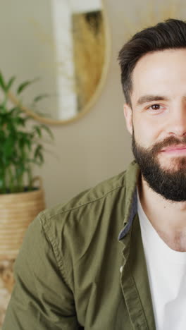 vertical half face video portrait of smiling, bearded caucasian man at home, with copy space