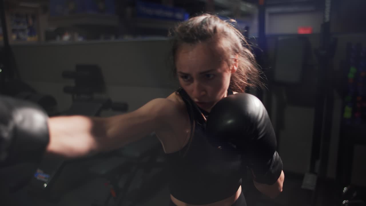 Female boxer punching camera during training in gloves