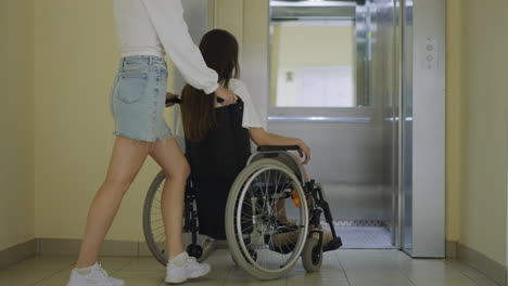 Woman-walks-in-elevator-pushing-wheelchair-with-sister