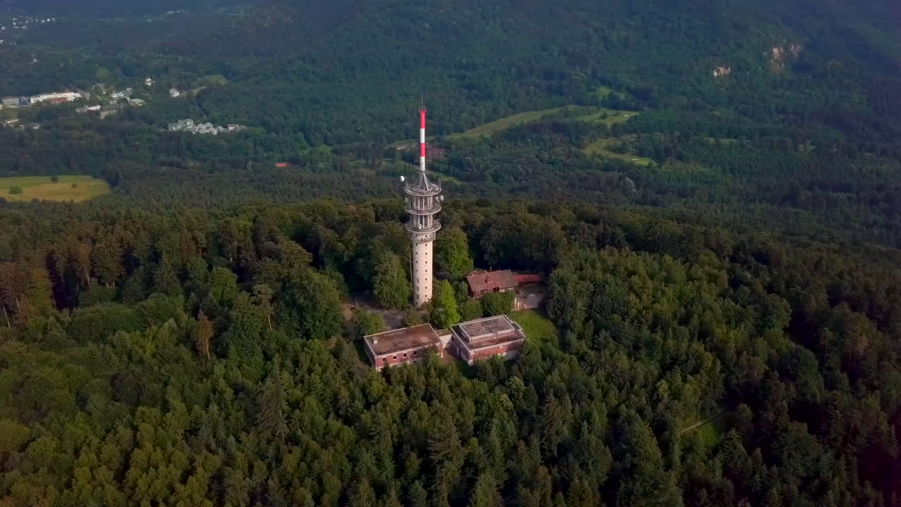 Surrounding aerial view from an elevated angle of the 'Fremersberg' transmission tower, Detailed view of the tower and surrounding buildings, revealing the spa town of Baden-Baden in the background