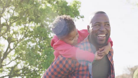 happy african american father and his son embracing in garden