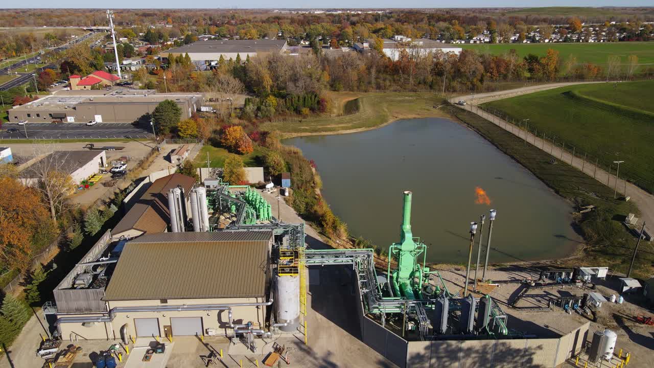 Drone video of landfill gas plant with flare stacks and retention pond