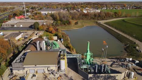 drone video of landfill gas plant with flare stacks and retention pond