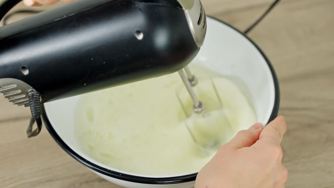 Whisking egg whites to create a soft peak texture with an electric hand mixer