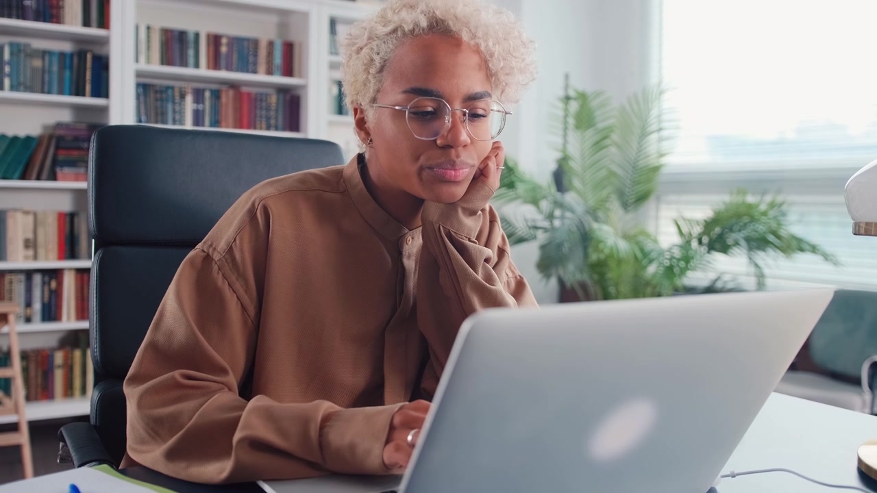 Young african american woman freelancer works using laptop sits at office desk