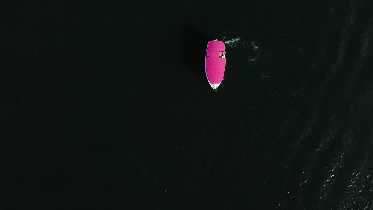 Aerial view of a pink Duffy boat doing circles