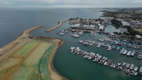 aerial flyover construction site field at port of coogee with parking yachts and boats during cloudy day - perth city,western australia