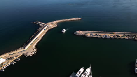 White-boat-entering-marina-near-Estepona-city,-aerial-drone-view