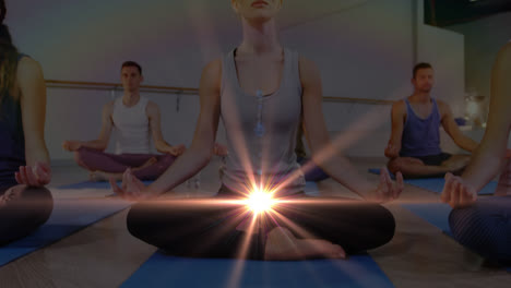 Animation-of-glowing-light-over-people-practicing-yoga