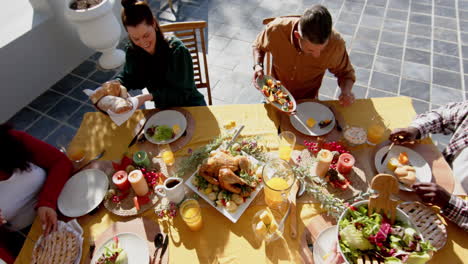 happy diverse male and female friends serving thanksgiving celebration meal in sunny garden