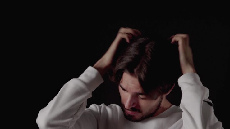 Trendy Young Man playing with andstraightening hair, close, black background