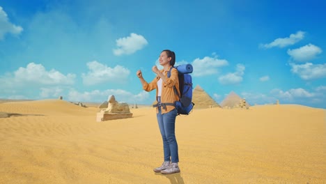 full body side view of asian female hiker with mountaineering backpack screaming goal celebrating the success while traveling in pyramid of giza
