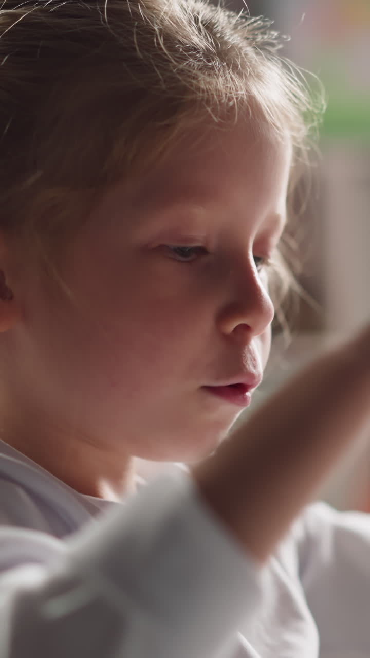 Clever little girl with thin braid counts elements on table wiggling lips during mental maths lesson in children room closeup slow motion