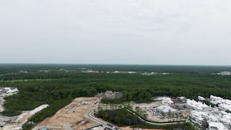 cerrando la vista en movimiento de bosques verdes y tierras disponibles para el desarrollo con algunos edificios y parte de la ciudad en la playa de arys