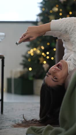 woman laughing while taking a photo on her phone at christmas