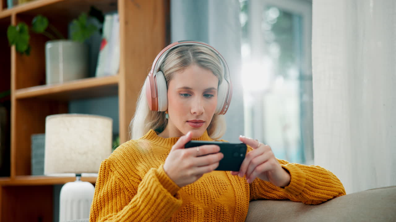 Woman playing video games on her mobile phone at home