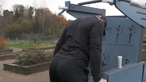 fit man utilizes park exercise equipment doing dips