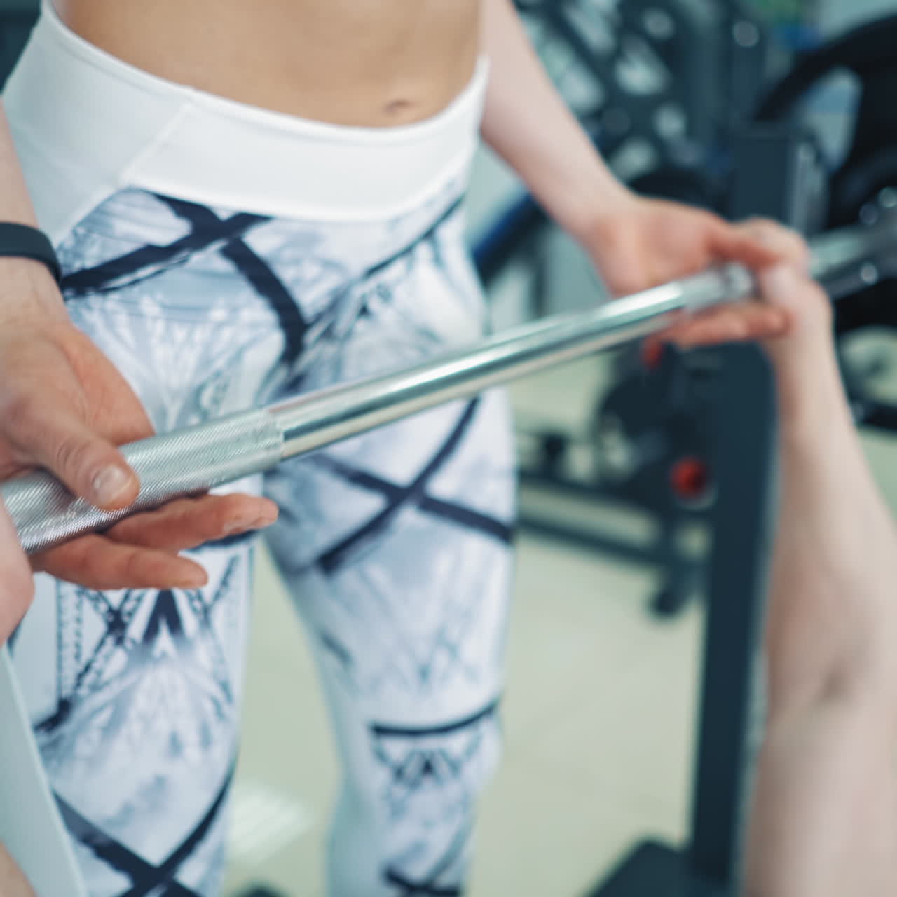 Strong bodybuilder lifting barbell in gym. Athletic man lying on special simulator and lifts barbell. Personal instructor woman helps athlete during training.