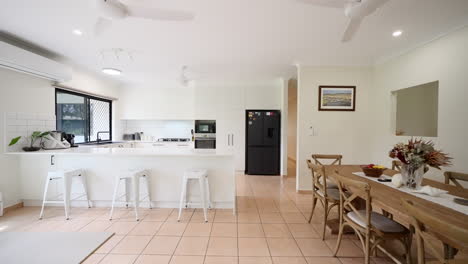 open plan dolly to dining kitchen from living room showcasing black fridge and appliances with clean white countertops