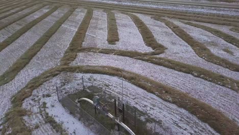 aerial: dusting of snow on gas pipeline monitor in prairie wheat field