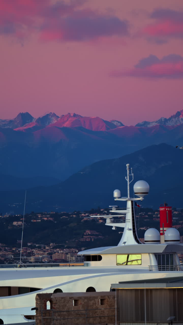 Multiple white boats docked in the Port Vauban, Antibes, France with the mountains on the background at sunset. Vertical