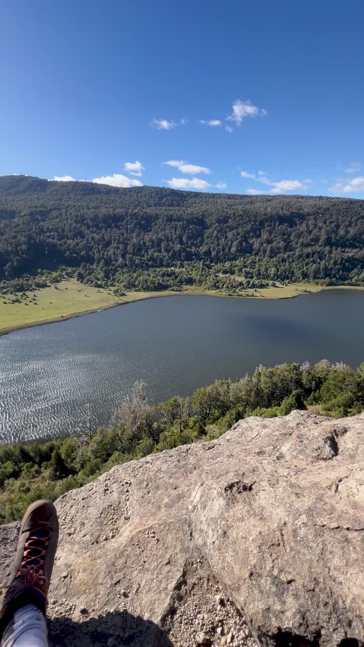 A breathtaking view from a rocky peak overlooking a serene lake and mountains