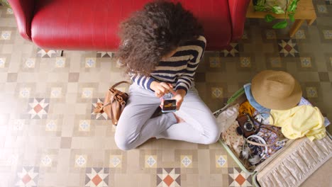 imágenes de video de 4k de una mujer usando su teléfono inteligente mientras hace las maletas para un viaje