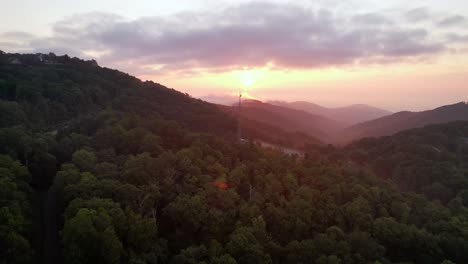 aerial push over treetops toward communications tower near boone nc, north carolina at sunrise