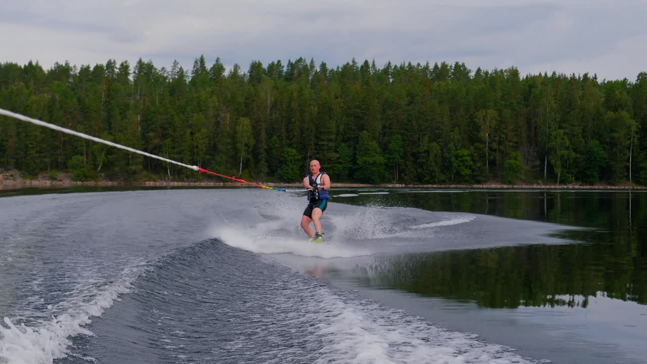 cámara lenta sobre un joven montando un wakeboard después de un barco deportivo en el archipiélago sueco en el sub3 de verano