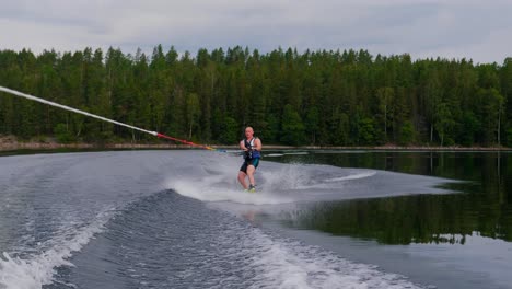 slowmotion over a young man riding a wakeboard after a sport boat in the swedish archipelago in the summer sub3