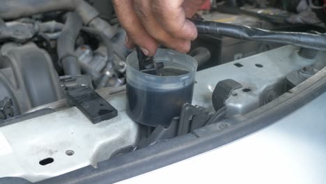 a close-up shot of a technicians' fingers dipping an integral part of a car's engine in oil to clean it while fixing the machine in a repair shop in bangkok, thailand