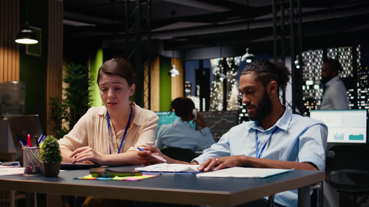 Middle Eastern man in wheelchair and woman CEO collaborating at night