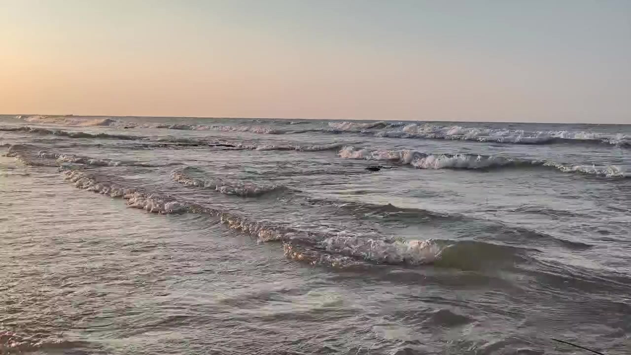 Dolci onde dell'oceano che si infrangono su una spiaggia sabbiosa al tramonto