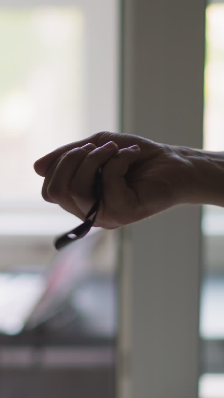 Happy owner hand throws and catches key with long fob having fun by terrace in light spacious apartment extreme close view slow motion