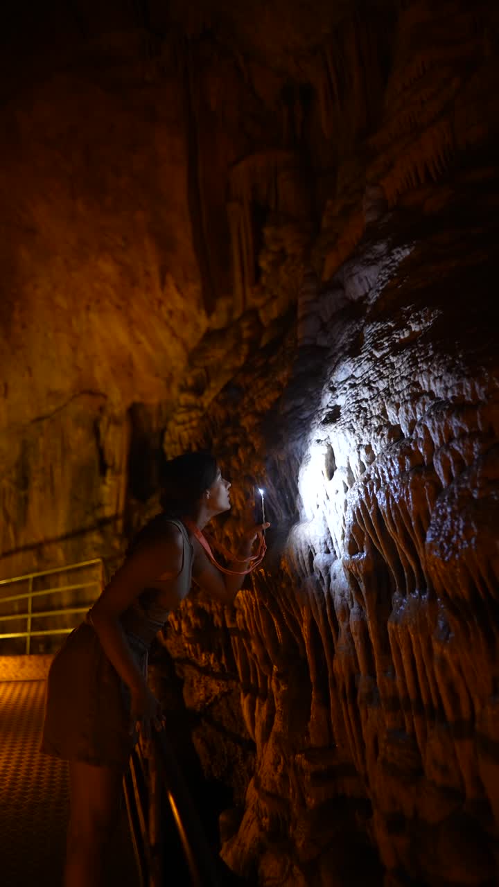 Woman Exploring a Cave with a Flashlight