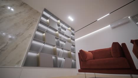 modern living area with custom-built storage cabinets featuring led backlighting, complemented by comfortable terracotta sofas