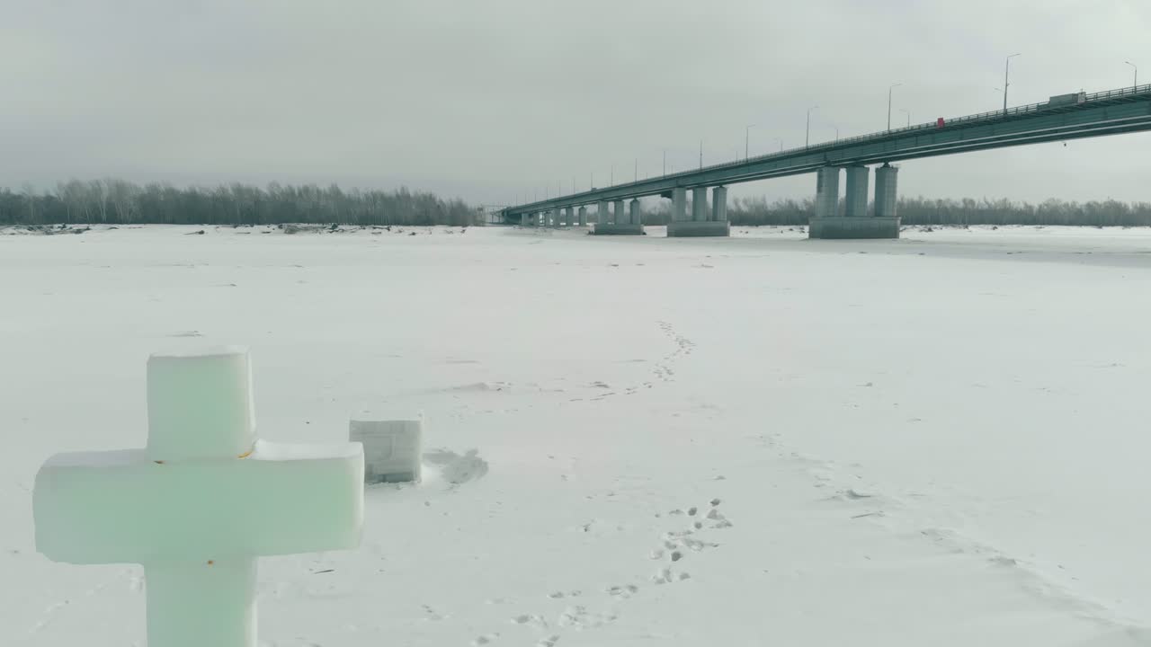 거대한 회색 다리가 있는 하얀 얼어붙은 강에 조각된 얼음 십자가