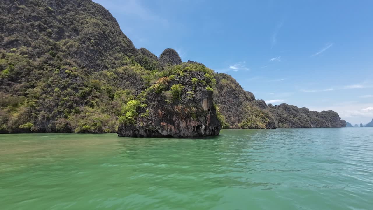 A scenic boat ride through towering limestone cliffs in Phang Nga Bay, Phuket, Thailand, featuring tropical waters, dramatic karst formations, and a popular travel destination