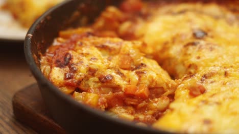 Unrecognizable-cook-cutting-yummy-gratin-with-veggies-and-tomato-sauce