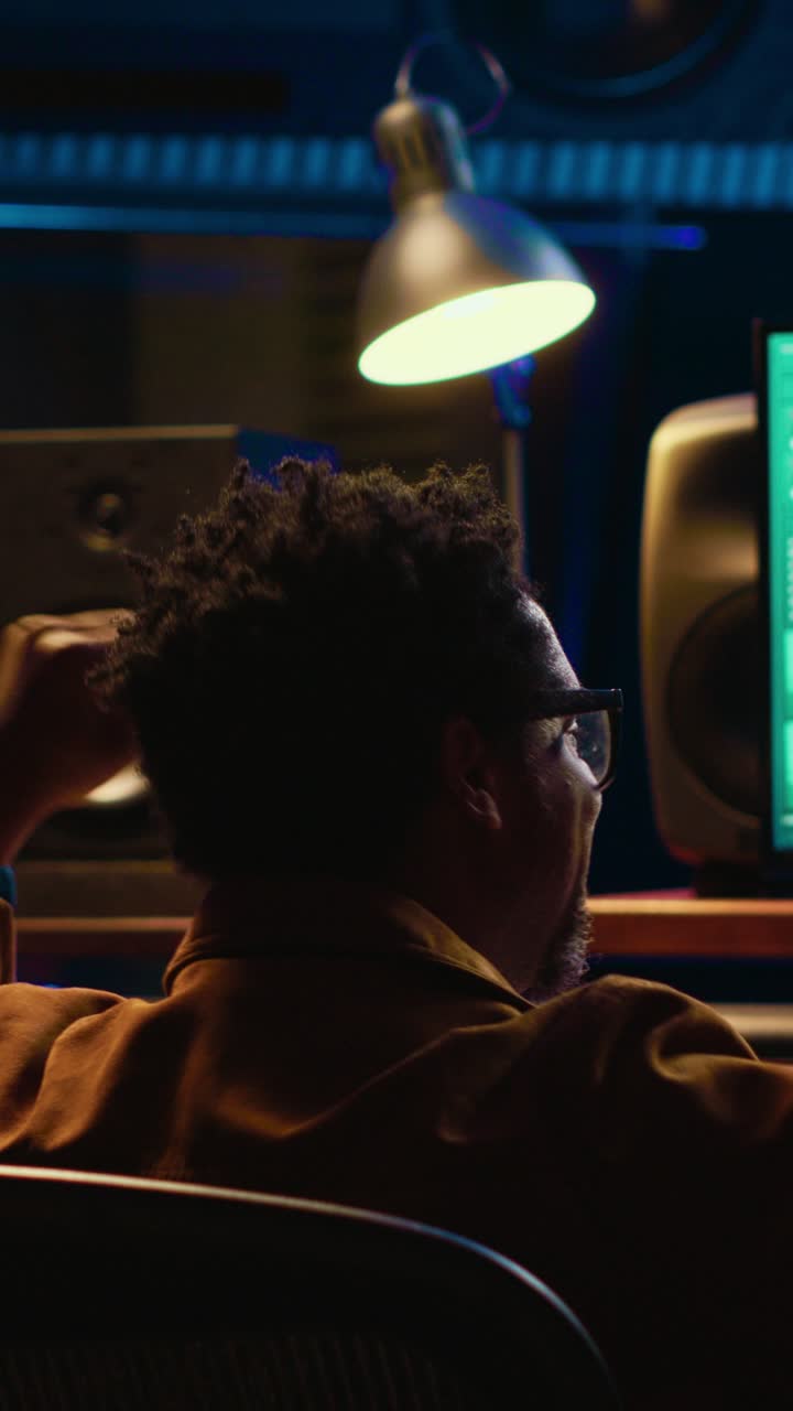 Uomo che lavora a un mixer audio in uno studio di registrazione buio