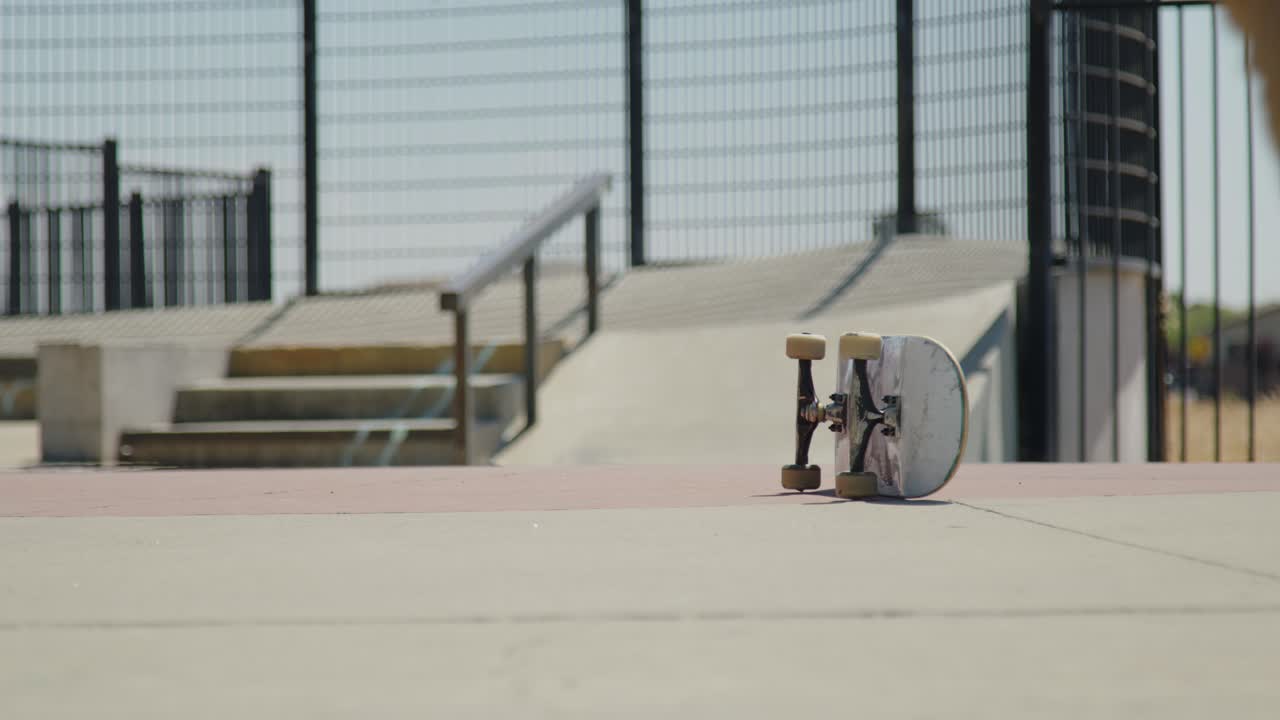 A skateboarder casually walks up to their board and steps onto it at the skatepark