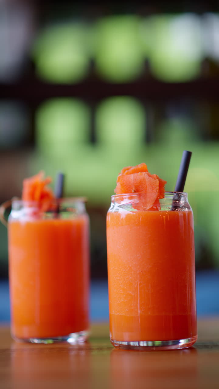 Two glasses of carrot juice, on the table at a restaurant. Vertical