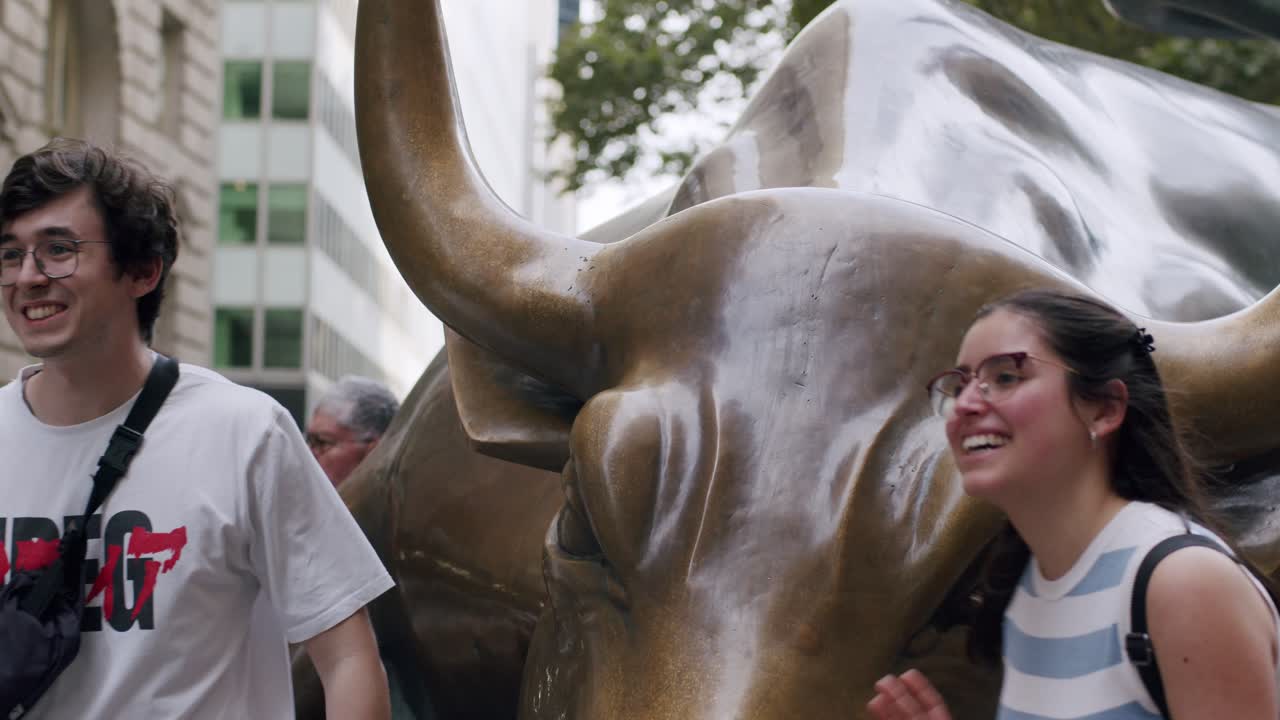 Young couple posing happily with Wall Street Charging Bull in New York City