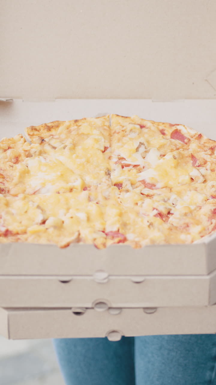 Delicious pizza in a box being held by a person