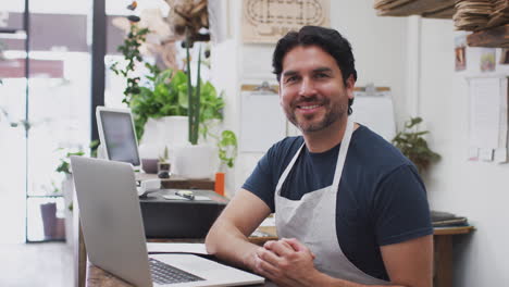 Retrato-De-Un-Asistente-De-Ventas-Masculino-Trabajando-En-Una-Computadora-Portátil-Detrás-Del-Mostrador-De-Ventas-De-Una-Floristería