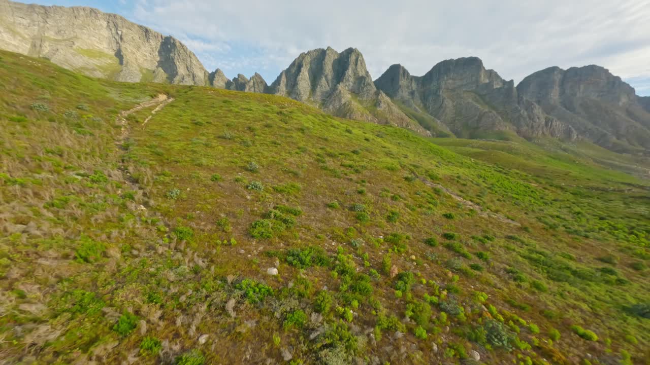 Drone in volo sopra le colline erbose verso le bellissime scogliere a Kogel Bay