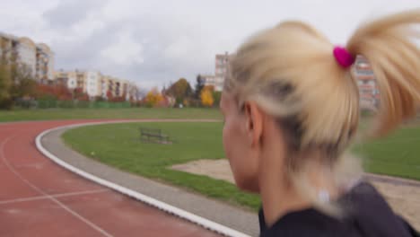 Joven-Atleta-Rubia-Caucásica-Mujer-Corriendo-Por-La-Mañana-En-Una-Pista-De-Atletismo